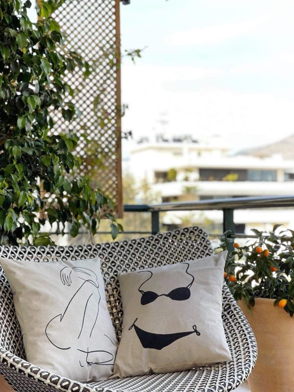 bikini beige cushion made of 100% cotton, with black bikini print, together with another cushion in a terrace armchair.