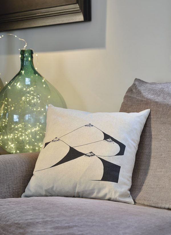 bodyscape beige cotton square cushion made of 100% cotton, with abstract design of a woman's chest on a sofa.