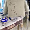 figura beige cushion made of 100% cotton, with print design of female figure’s back on a marble table with back mirror.
