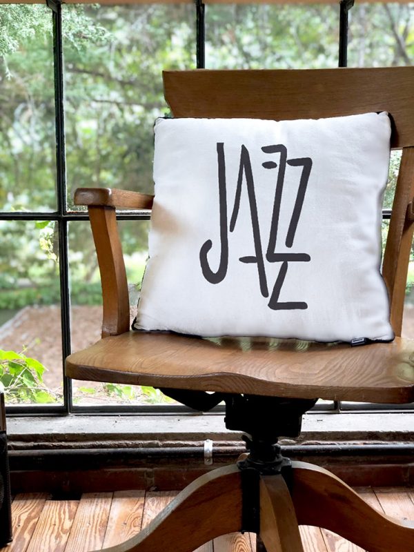 jazz white cushion made of 100% cotton, with a wonderful print of the word jazz on a wooden director's chair.