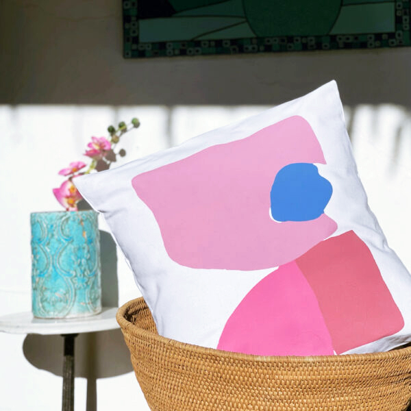 lara pink Linen white garden cushion 46x46 with geometric patterns in pink tones outdoors on a wicker basket.