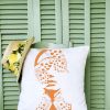 Madame butterfly Linen white garden cushion 46x46 with female face design with butterflies on a chair in front of green wooden shutters.