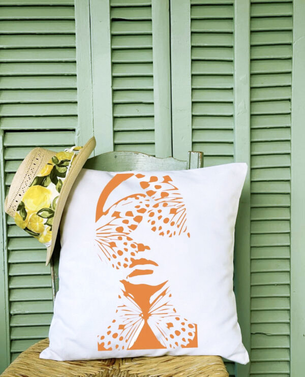 madame butterfly Λινό λευκό μαξιλάρι κήπου 46x46 με σχέδιο γυναικείο πρόσωπο με πεταλούδες πάνω σε καρέκλα μπροστά από πράσινα ξύλινα μπατζούρια.