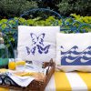 madeleines Linen white garden cushion 46x46 with blue butterflies on a metal blue outdoor sofa along with a decorative breakfast tray.