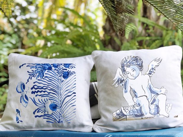 mimosa Linen white garden cushion 46x46 with blue plant design and leaves outdoors with lots of green.