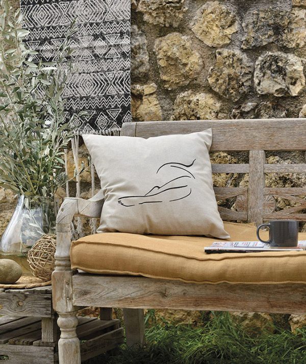 muse beige cushion made of 100% cotton, outline design female body lying on a wooden garden bench.