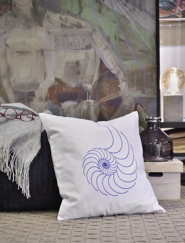 nautilus I Linen white cushion 46x46 with blue shell outline design on the floor of an indoor winter house.