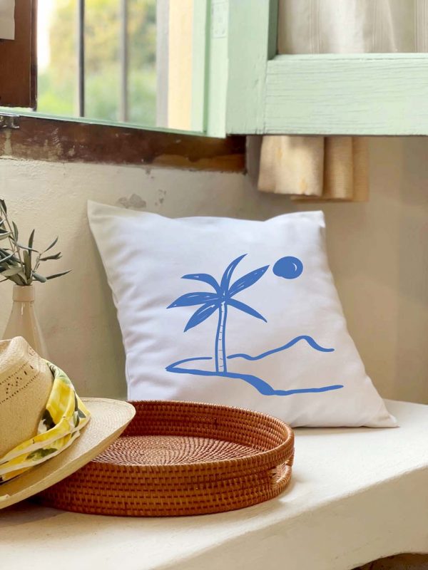 palmera Linen white cushion 46x46 with blue palm print on an island on a sofa outside the house.