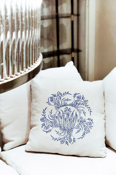 Διακοσμητικό μαξιλάρι σε λευκό χρώμα με ιδιαίτερο γαλάζιο σχέδιο λουλουδιών πάνω σε λευκό καναπέ