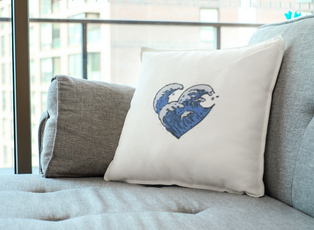 Λευκό διακοσμητικό μαξιλάρι με τυπωμένο σχέδιο μπλε καρδιά από κύματα τοποθετημένο σε μπεζ γκρι καναπέ