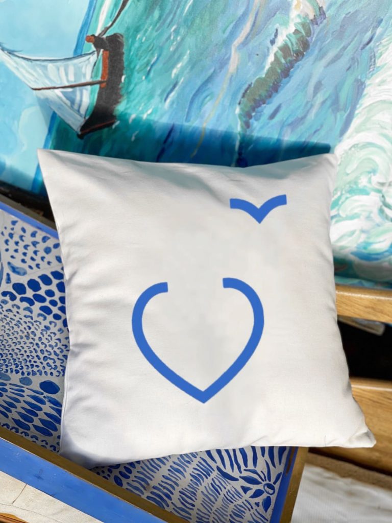 Διακοσμητικό μαξιλάρι σε λευκό χρώμα με ιδιαίτερο γαλάζιο σχέδιο αφηρημένης καρδιάς σε καθιστικό χώρο σπιτιού